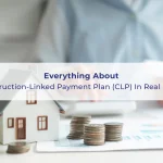 Miniature house model with stacked coins on a table, symbolizing property investment and Construction-Linked Payment Plan (CLP) in real estate, with a person reviewing documents in the background.